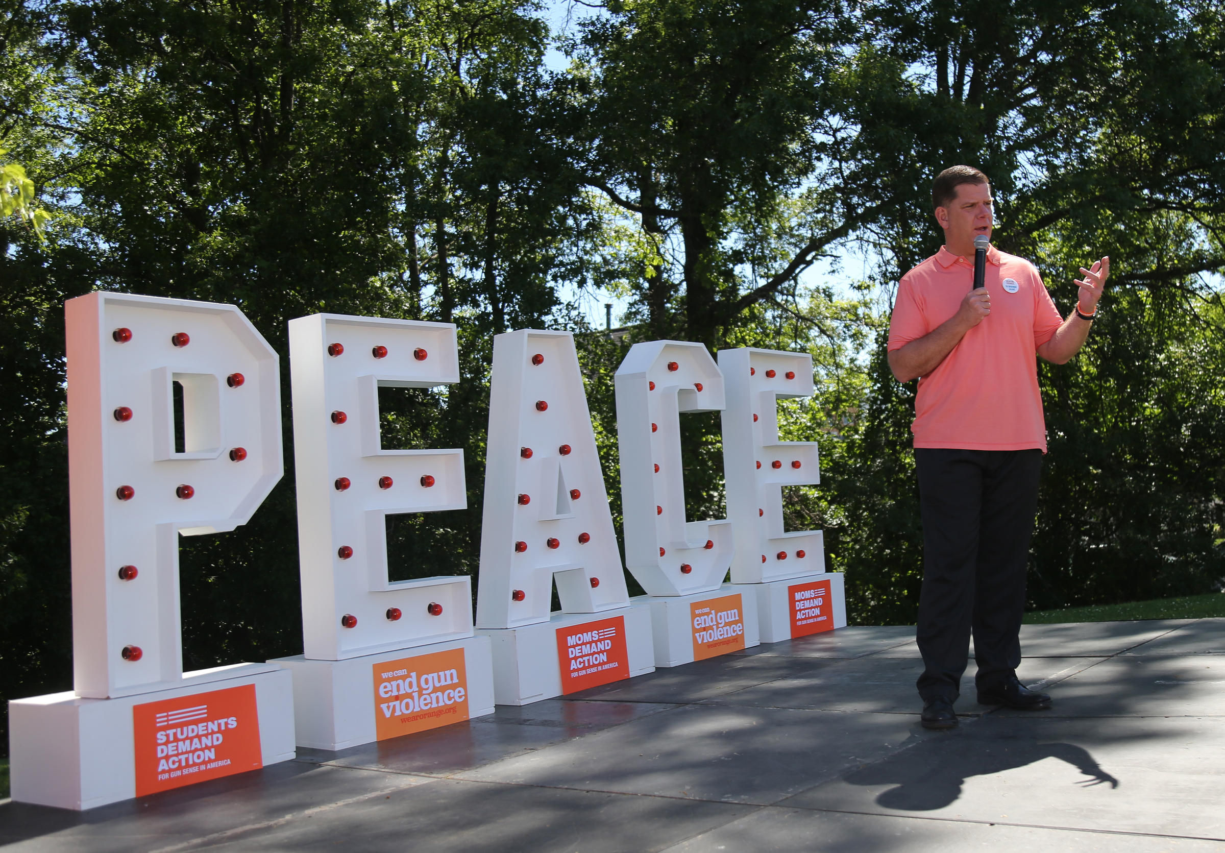 Mayor Walsh speaking at even in front of Peace sign