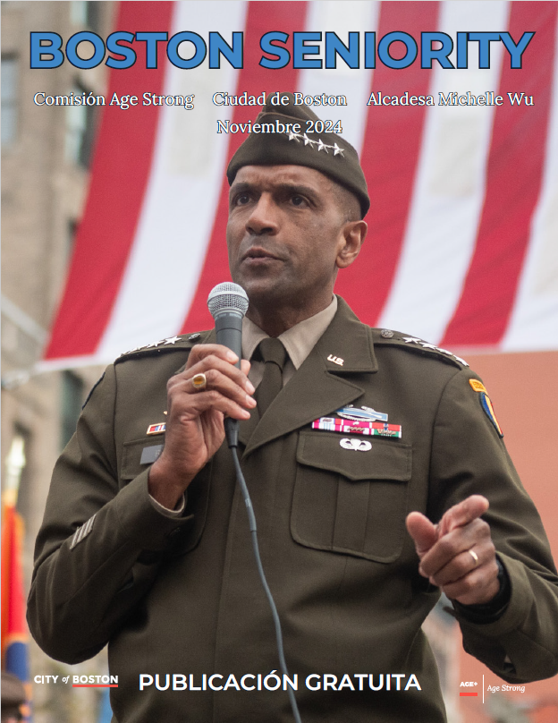 November 2024 Cover of Boston Seniority Magazine, featuring a veteran from a Veterans Day celebration in Boston speaking into a microphone with the flag of the United States of America waving behind him.