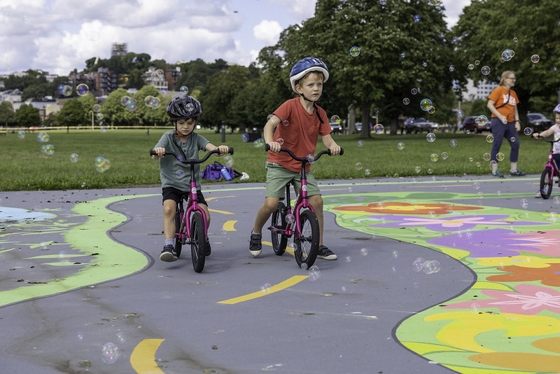 Two kids ride bikes at a Bike Town