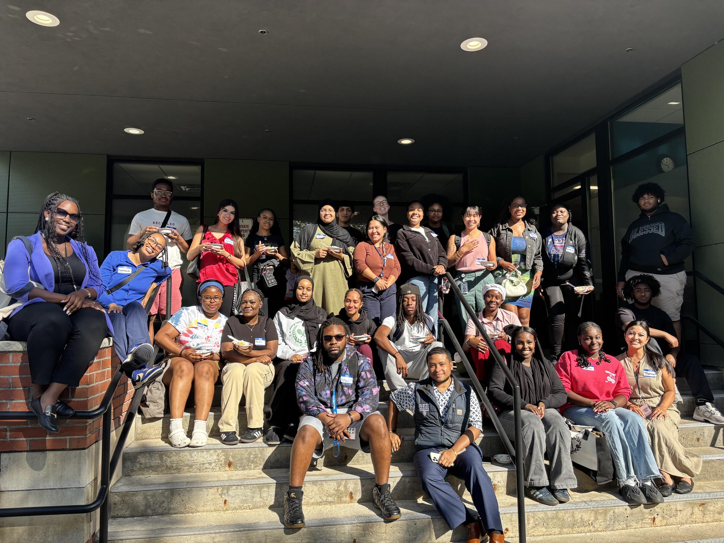 A group of Generational Health Scholarship recipients and Boston Public Health Commission staff members coming together for a photo on the steps of a building.