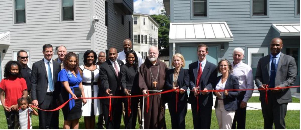 City officials, the Cardinal, and community members celebrate the Cote Village opening with a ribbon cutting.