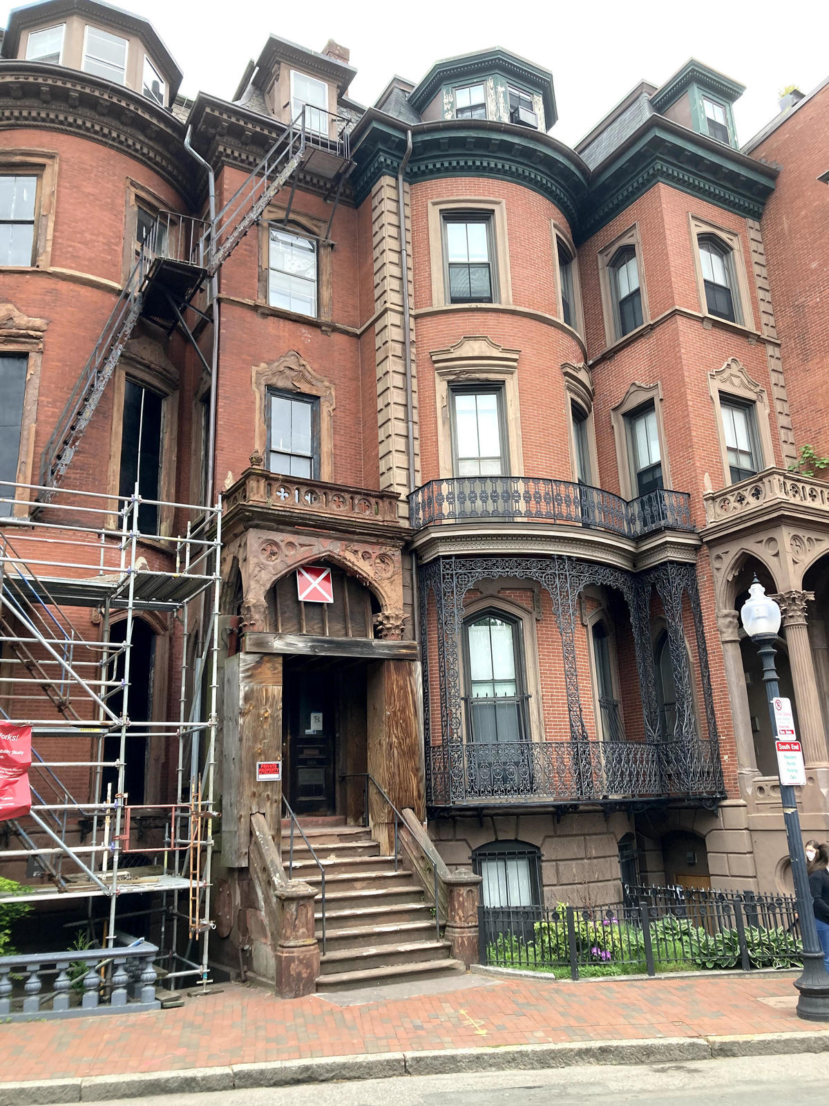 A 3-story brick townhouse with ornate decoration and a scaffolding partially obscuring half of the building