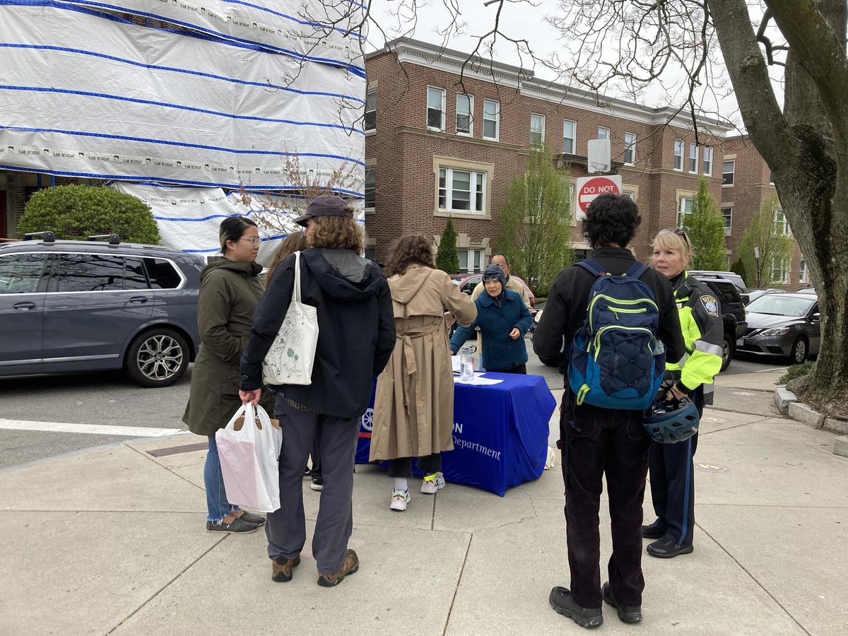 Photo of people standing around a table on the sidewalk talking