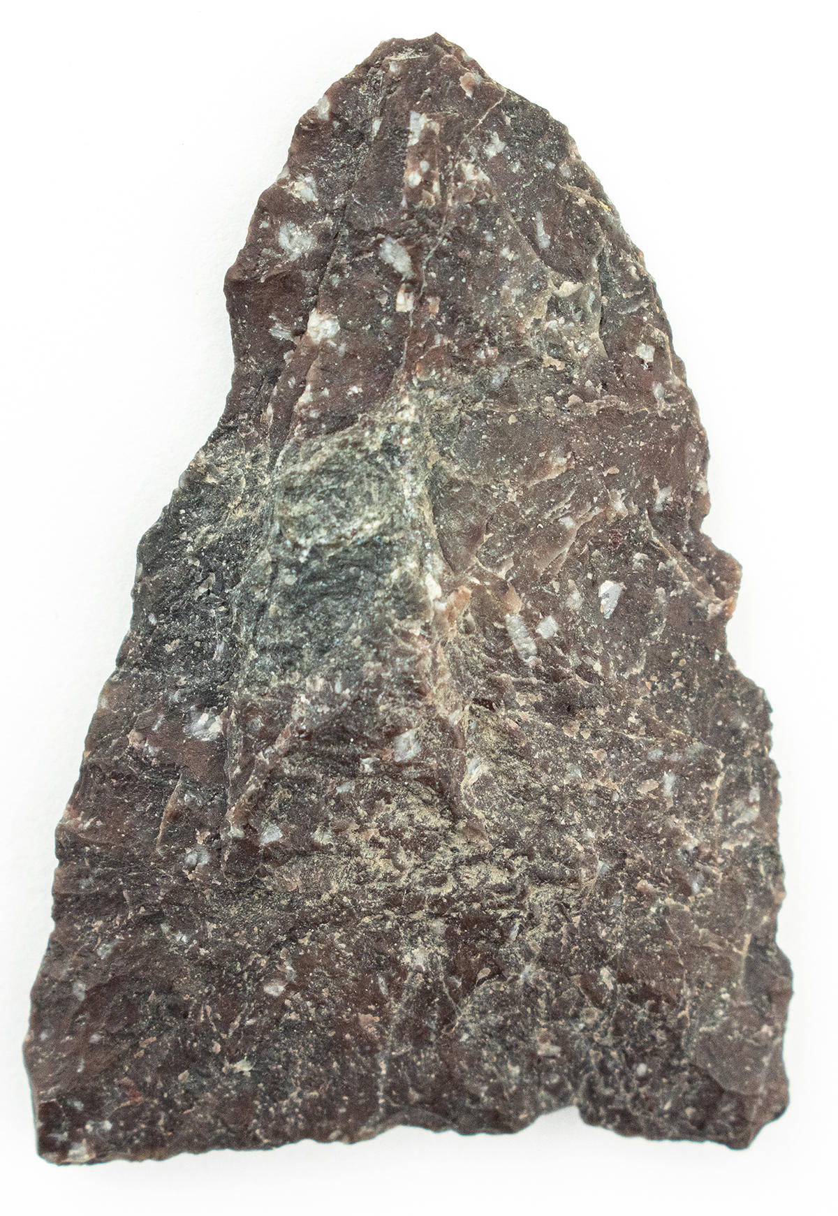 Close-up of a roughly triangular Native projectile point made from Lynn rhyolite, a deep reddish stone with white veins and phenocrysts.
