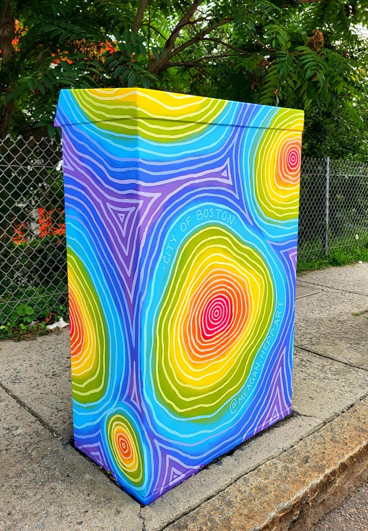 Painted utility box with concentric, rounded shapes in rainbow colors