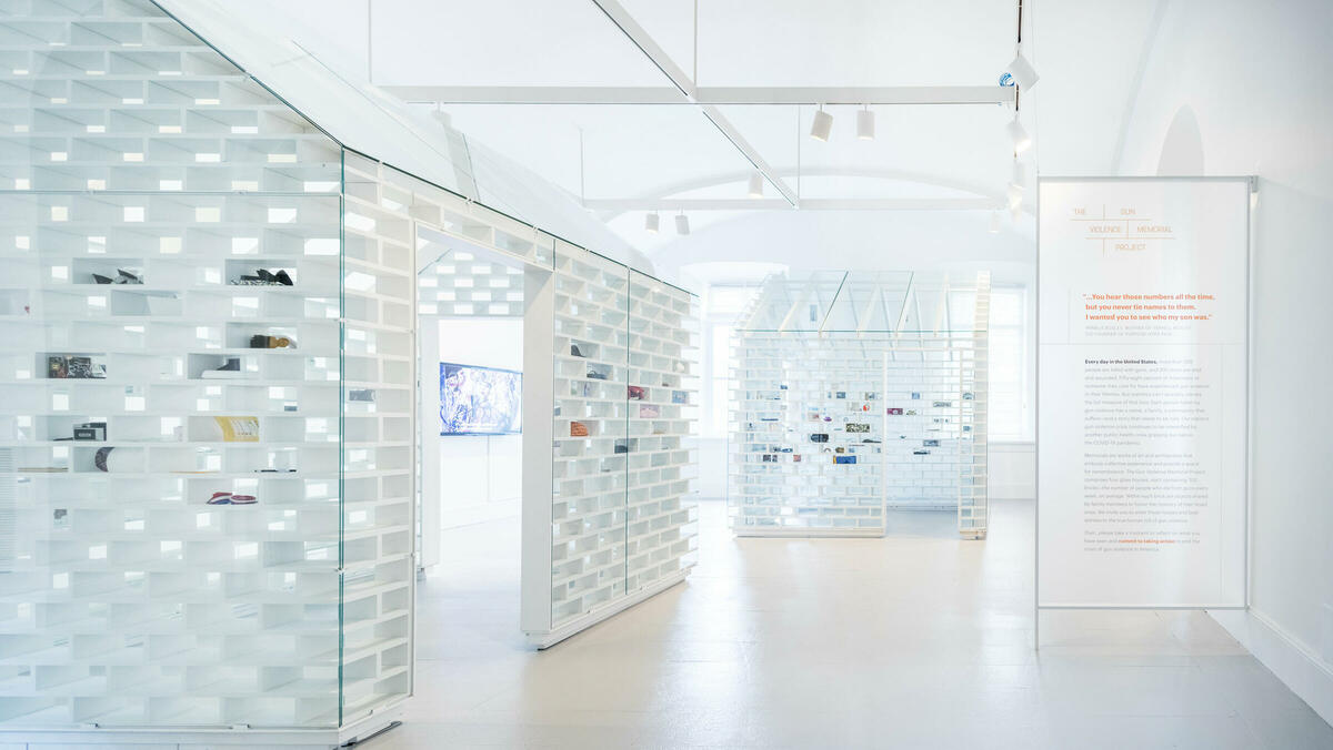 Image of two houses built of 700 glass bricks. Each house representing the average number of lives taken due to gun violence each week in America. 