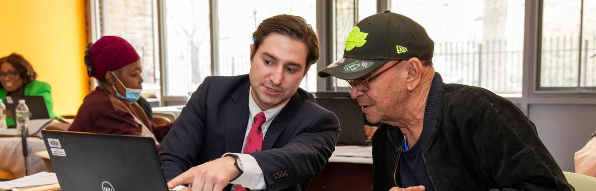 A digital equity worker for the City of Boston guides a resident through a computer task.