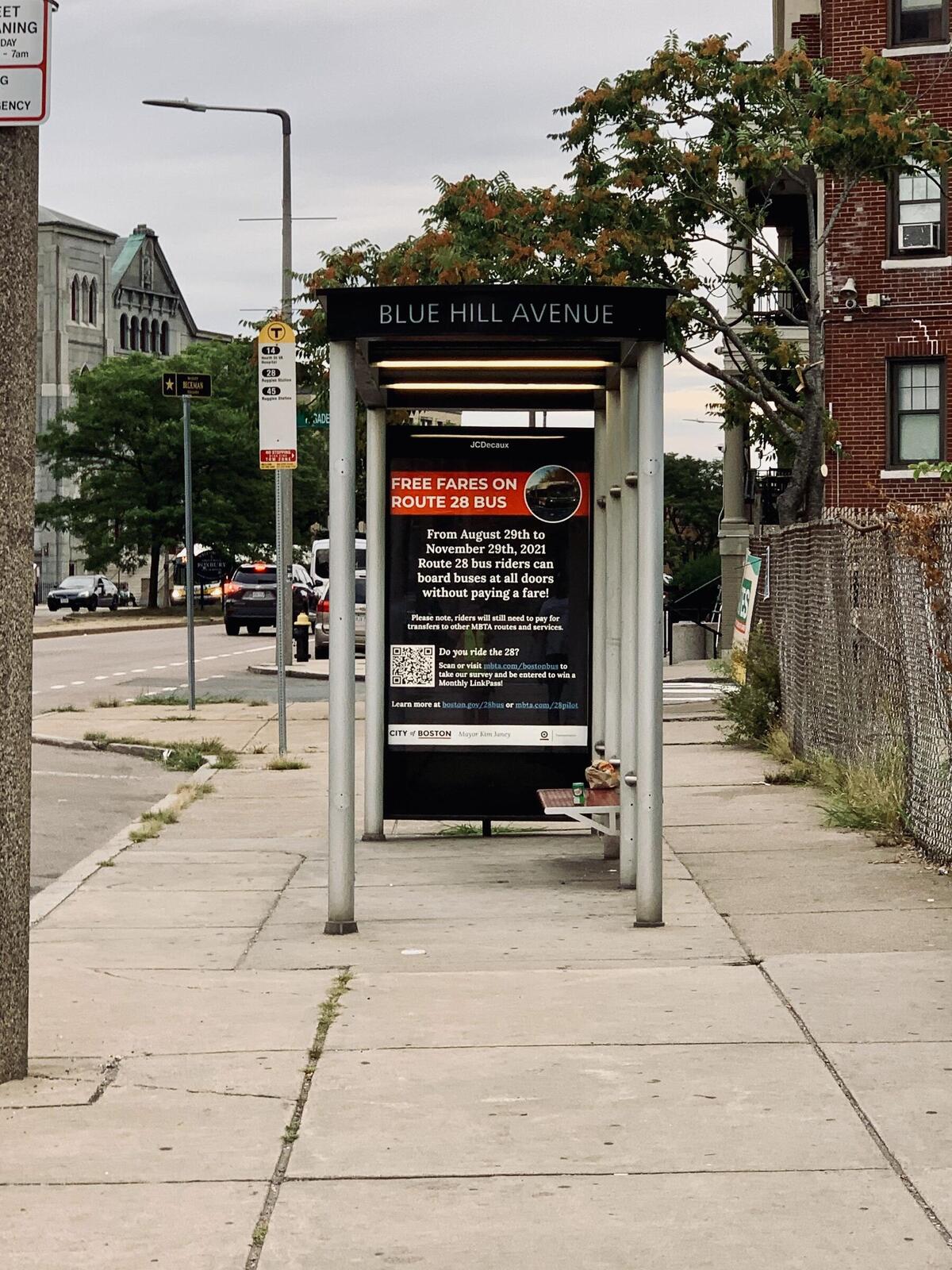 Bus shelter at route 28 bus stop on blue hill Ave. Shelter is displaying advertisement for a fare free Route 28