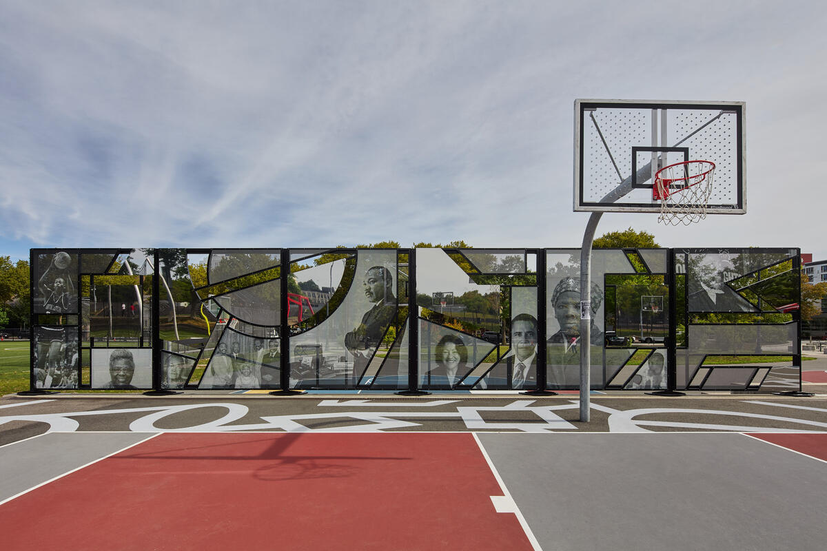 A wall featuring figures from Black history divides a basketball court from other recreational areas