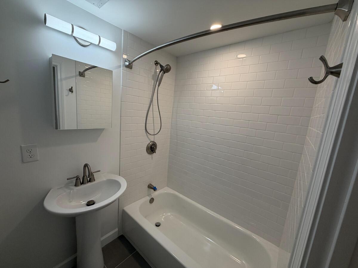 Pedestal sink, vanity mirror, and combination tub and shower.