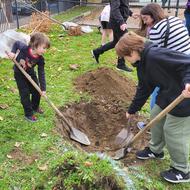 Three children dig a hole with spades in Hobart Park.