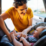 Mother putting baby is carseat