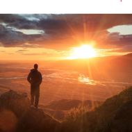 Man on hill watching sunrise