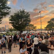 Families enjoying a concert in the park with sunset.