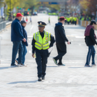 Boston Police Officer walking. People walking behind him.