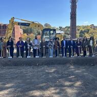 A row of 15 people with shovels celebrate the groundbreaking at Mission Hill Pathway