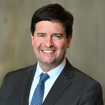 Adam Cederbaum wearing a suit with a blue tie