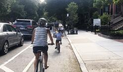 A family rides bikes together in a separated bike lane on Beacon Street